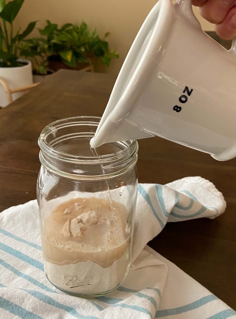 image of flour in a glass jar on table and water being poured into jar
