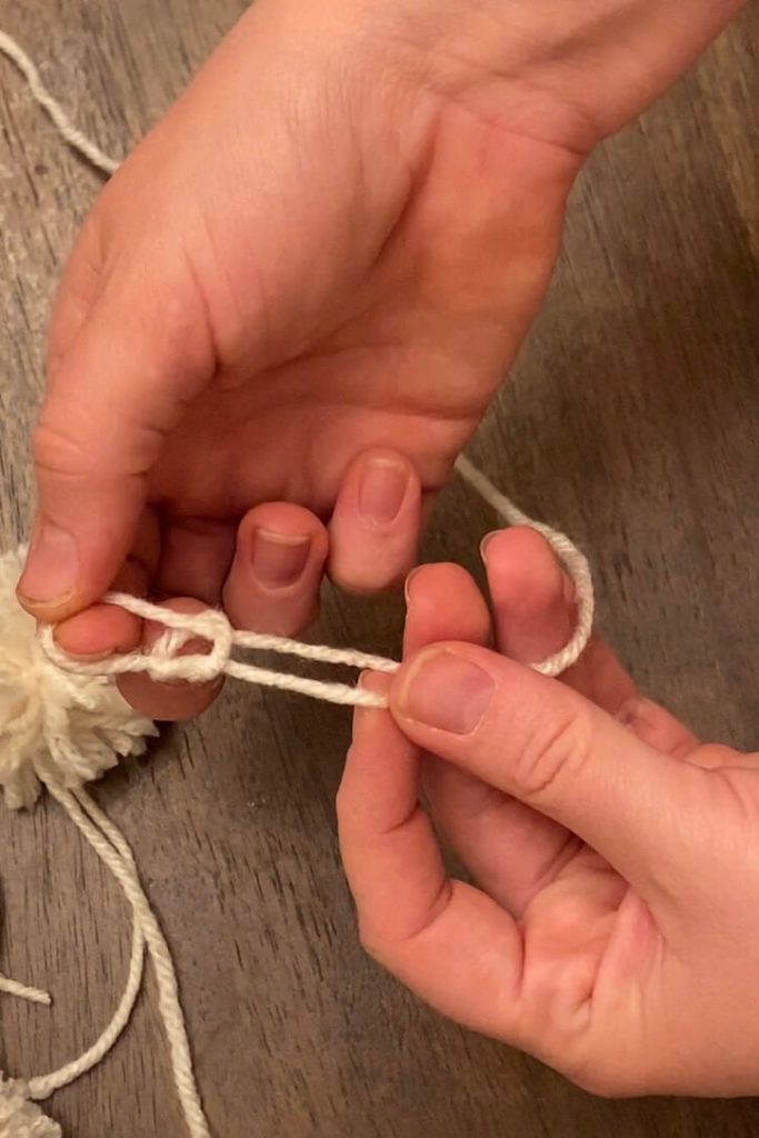 woman's hands beginning a chain loop in cream yarn on table