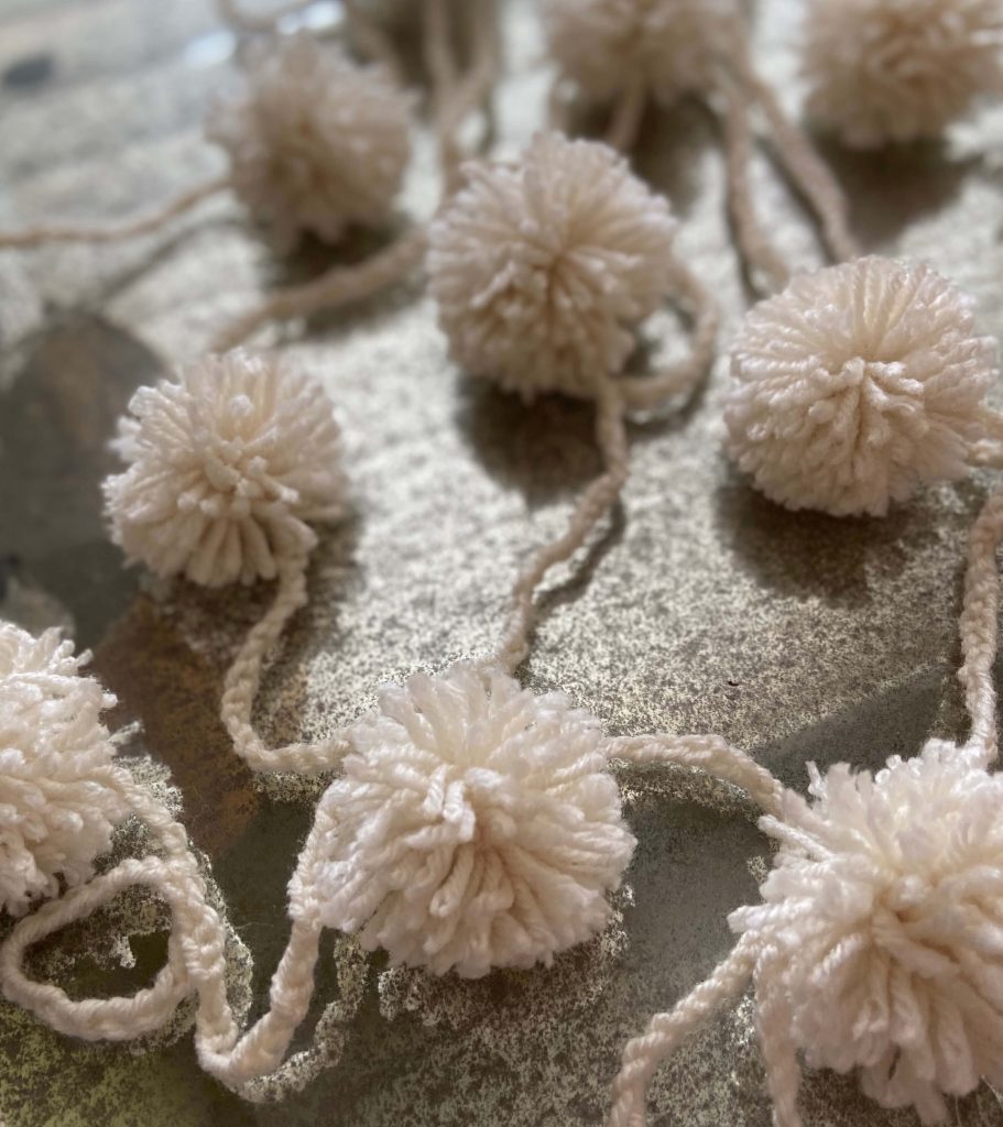 close up image of pom pom yarn garland on mercury glass table