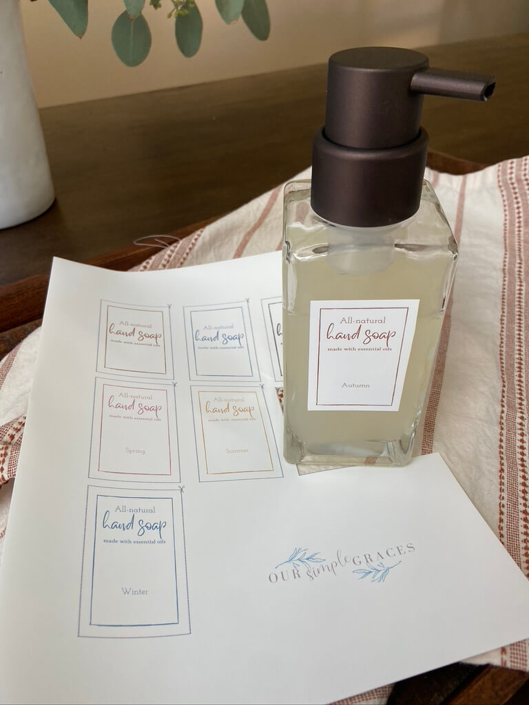 image of glass jar foaming hand soap with printed out soap labels on table sitting on towel