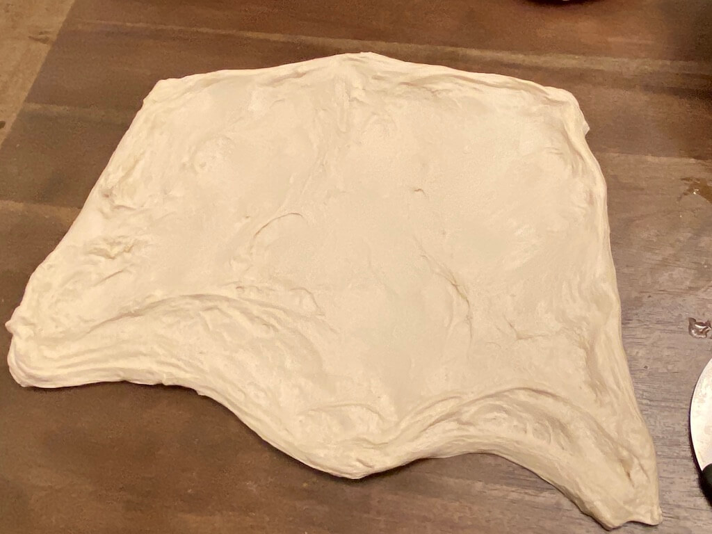 Sourdough dough stretched out on wood table