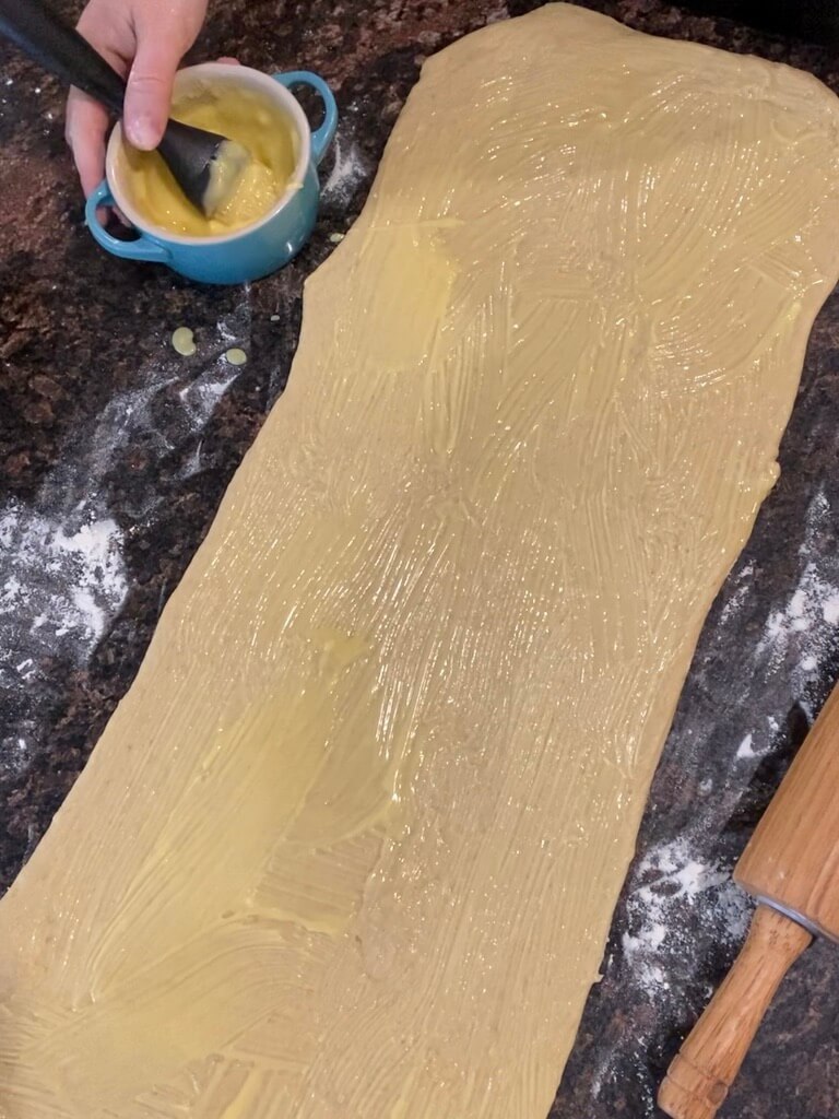 spreading butter on sourdough brioche dough