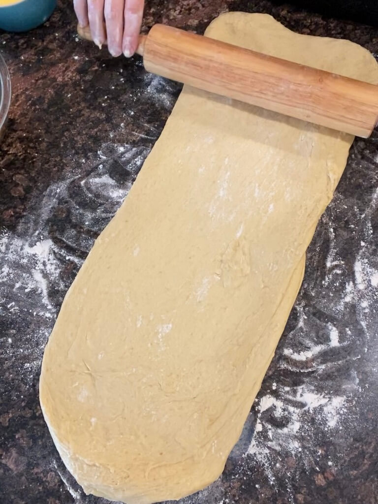 rolling pin rolling out sourdough brioche dough on floured counter