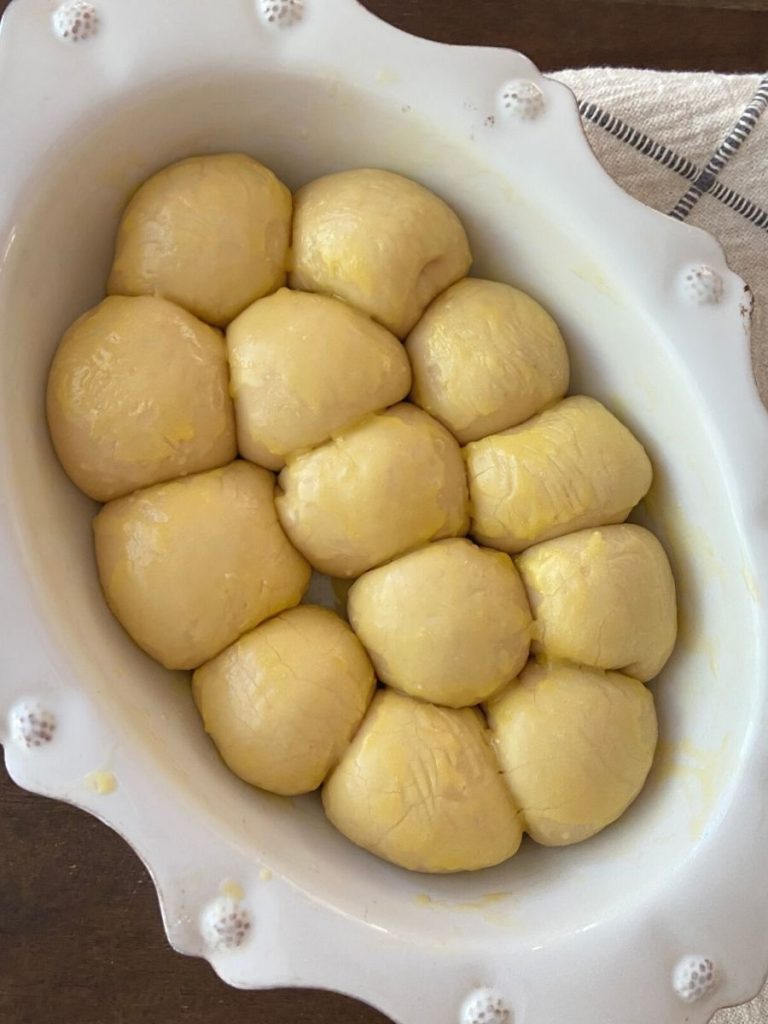 sourdough rolls dough after second rise with butter on top in white dish