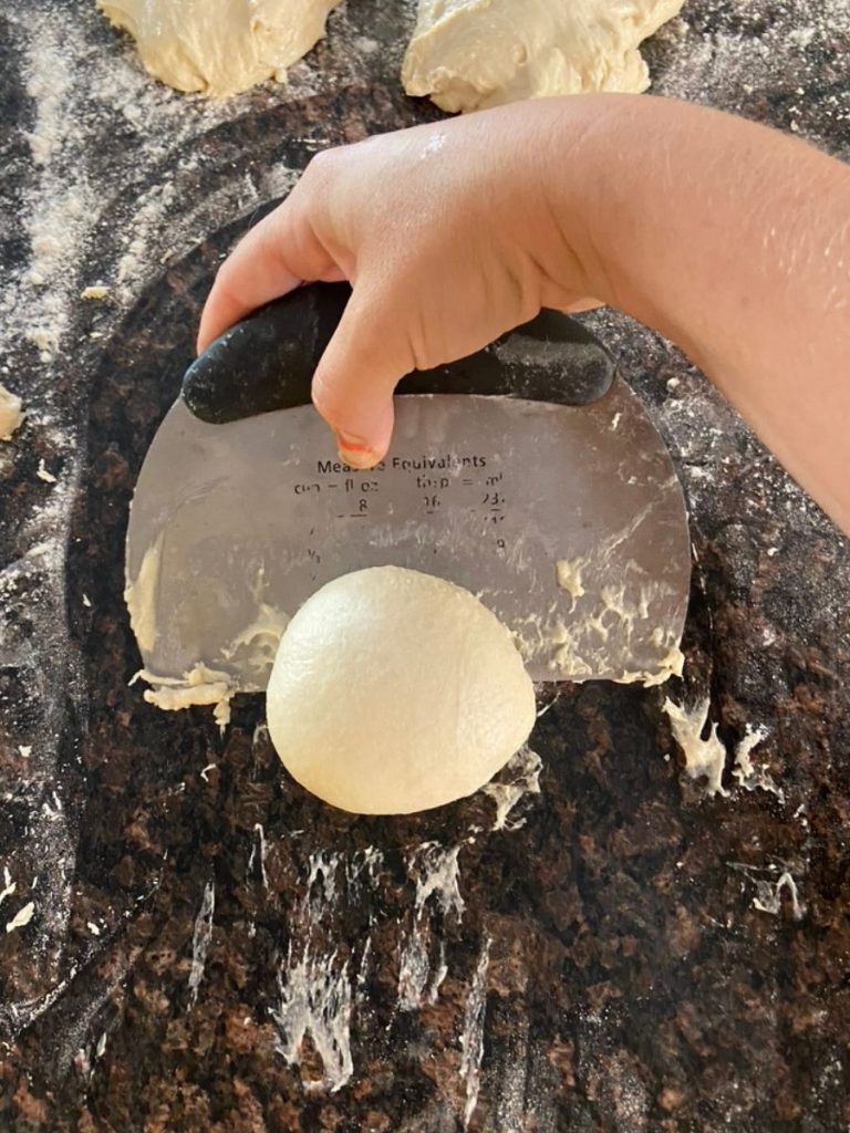 bench scraper pulling dough ball to build tension