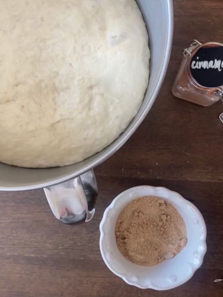 image of risen dough with cinnamon and bowl of cinnamon sugar