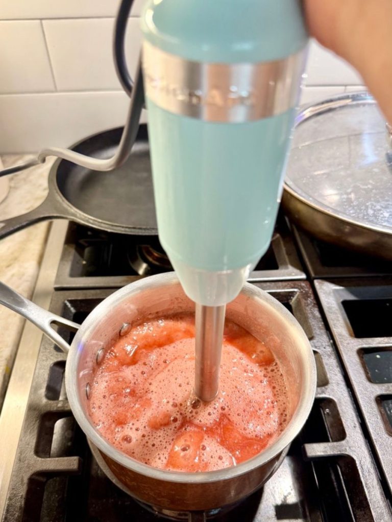 immersion blender blending strawberries in saucepan